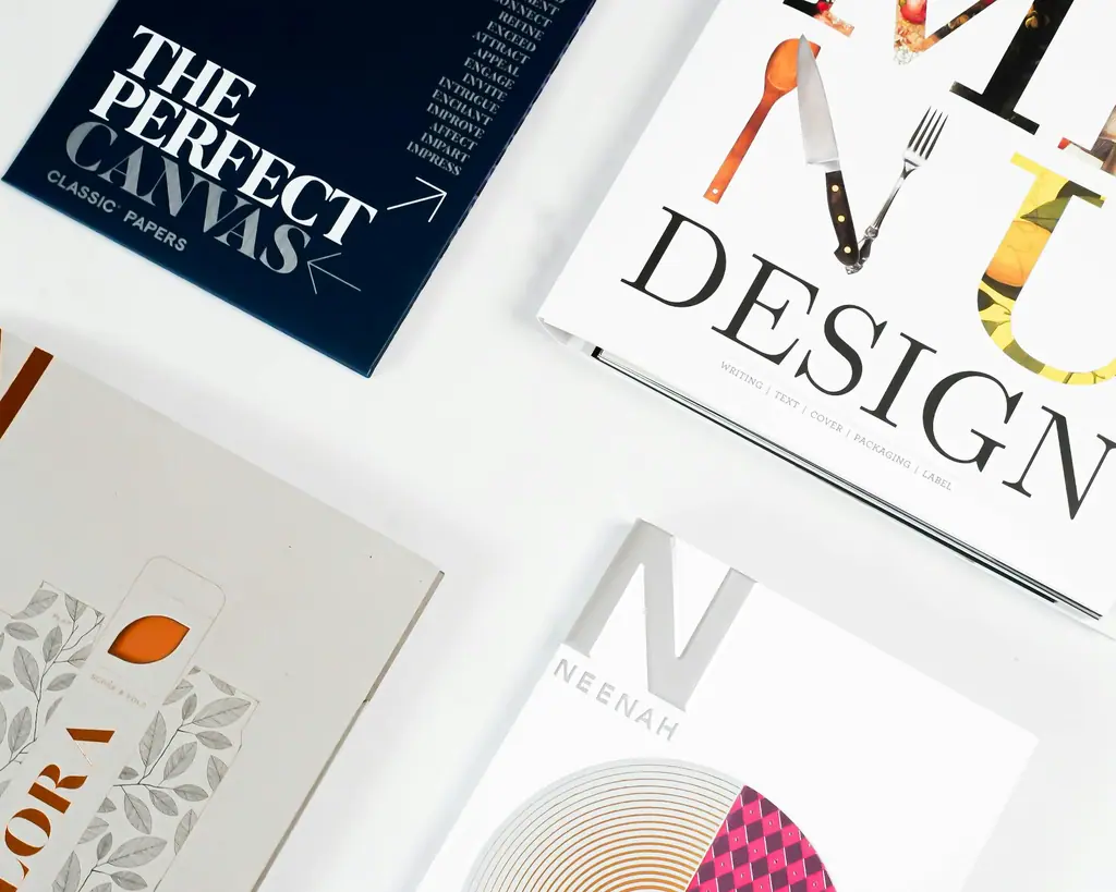 Printed brand collateral and design magazines laid flat on a white surface