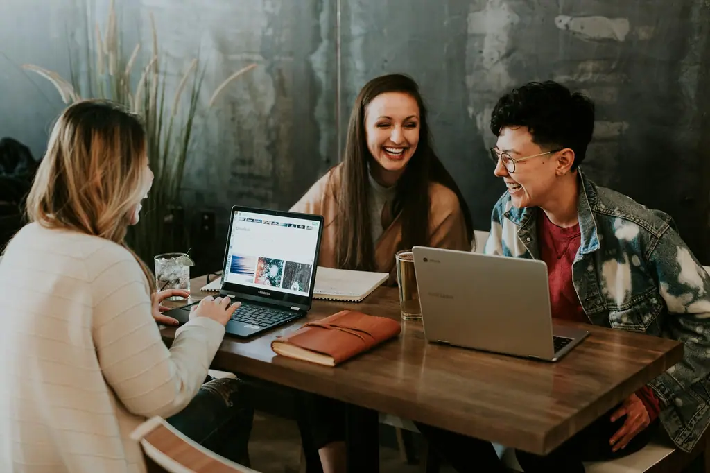 Team laughing around a table with laptops and notebooks in a brand positioning workshop