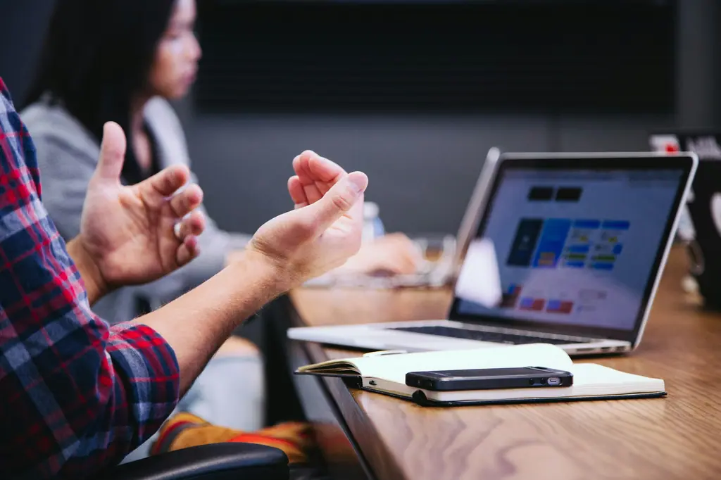 Hands gesturing beside a laptop showing an investor pitch deck during a meeting
