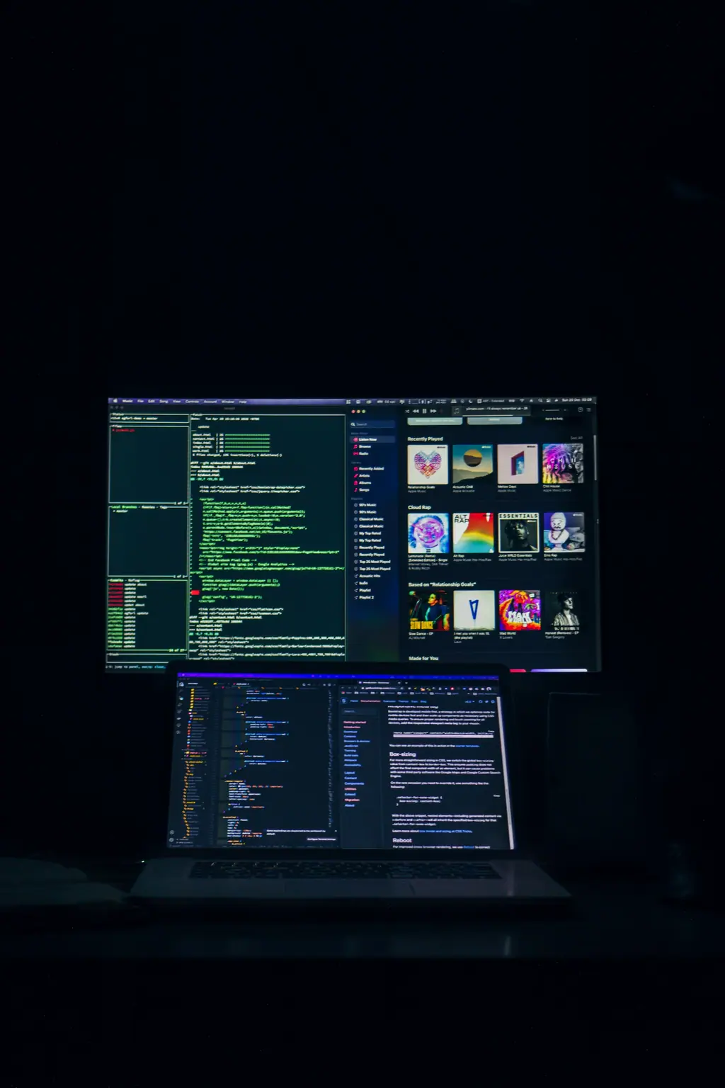 Developer workstation showing website code and interface design on dark monitors